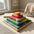 Hicooo multicolor Montessori wooden building blocks arranged in a pyramid on a wooden tray in a sunlit playroom.