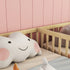 Children's room with a crib and plush elephant toy against a pink wall.