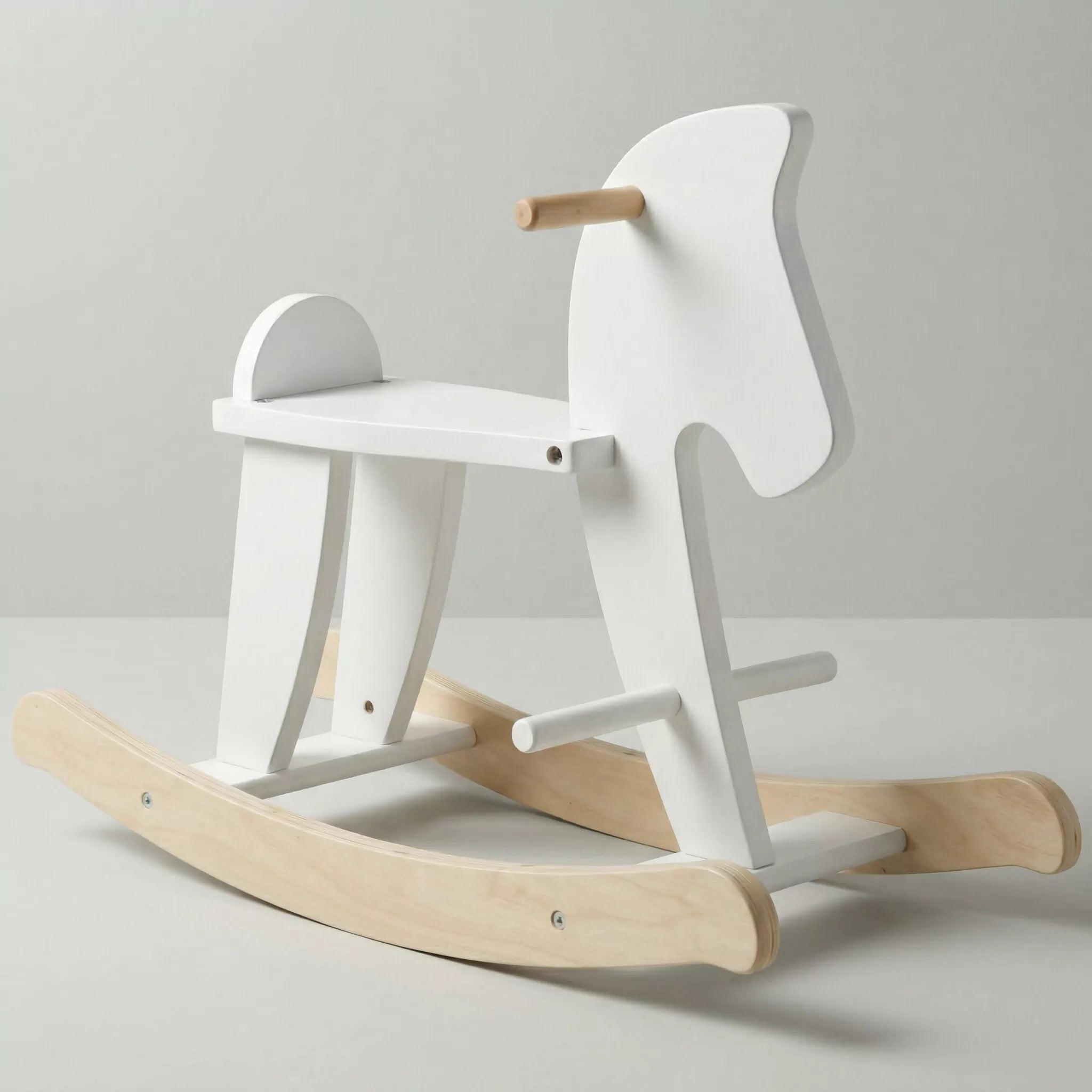 A studio product photograph of a classic wooden rocking horse featuring a natural wood finish, a smooth saddle seat, handlebars, and footrests, set against a plain background.