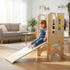 Laughing toddler girl sliding down the wooden ramp of a Hicooo convertible learning tower, transformed into an indoor playground slide