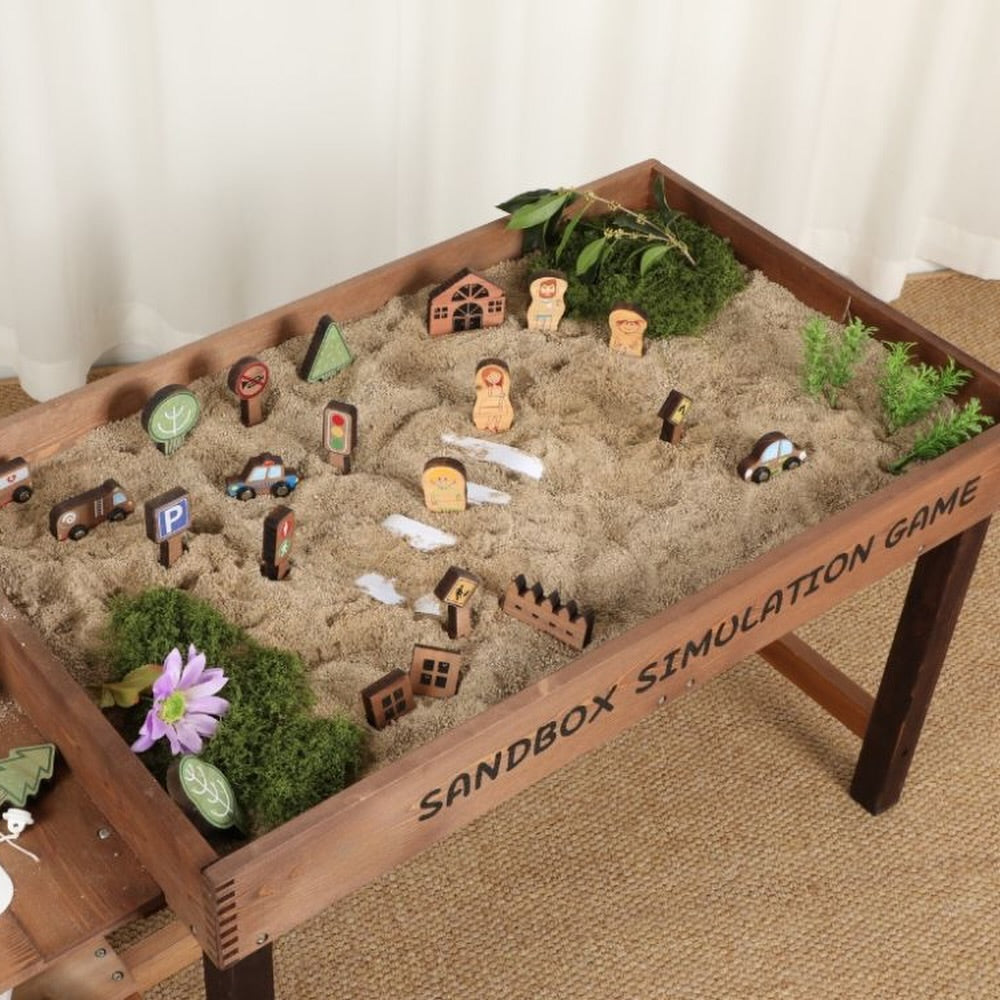  Elevated wooden sandbox for kids filled with sand and miniature city toys including wooden cars, road signs, houses and trees for imaginative outdoor play