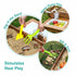 Elevated wooden sandbox and water table set up in a backyard garden with colorful pinwheel, toy vegetables, collapsible green bucket and wire mesh basket