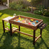 Elevated wooden sandbox set up on outdoor lawn with colorful sand toys including shovels, rakes, starfish molds, sand castles, toy trucks, water basin and green collapsible bucket