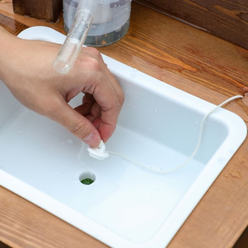 Close-up of white removable water basin tray with drain plug on elevated wooden sandbox for kids, showing easy water flow and cleanup design