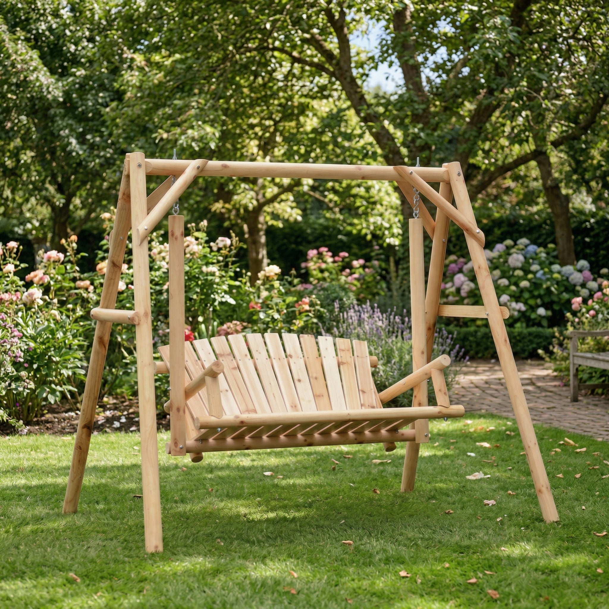 A lifestyle photograph capturing a freestanding rustic wooden log A-frame swing set with a stand, placed on a grassy lawn next to a brown wooden house and a patio in a sunny garden backyard.