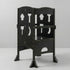 A black pine wood foldable toddler tower standing against a light grey background. The kitchen helper stool features cutout shapes resembling kitchen utensils like a spatula and rolling pin on its side panels.