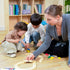 Parent guiding toddler to build wooden railway track, educational toy play