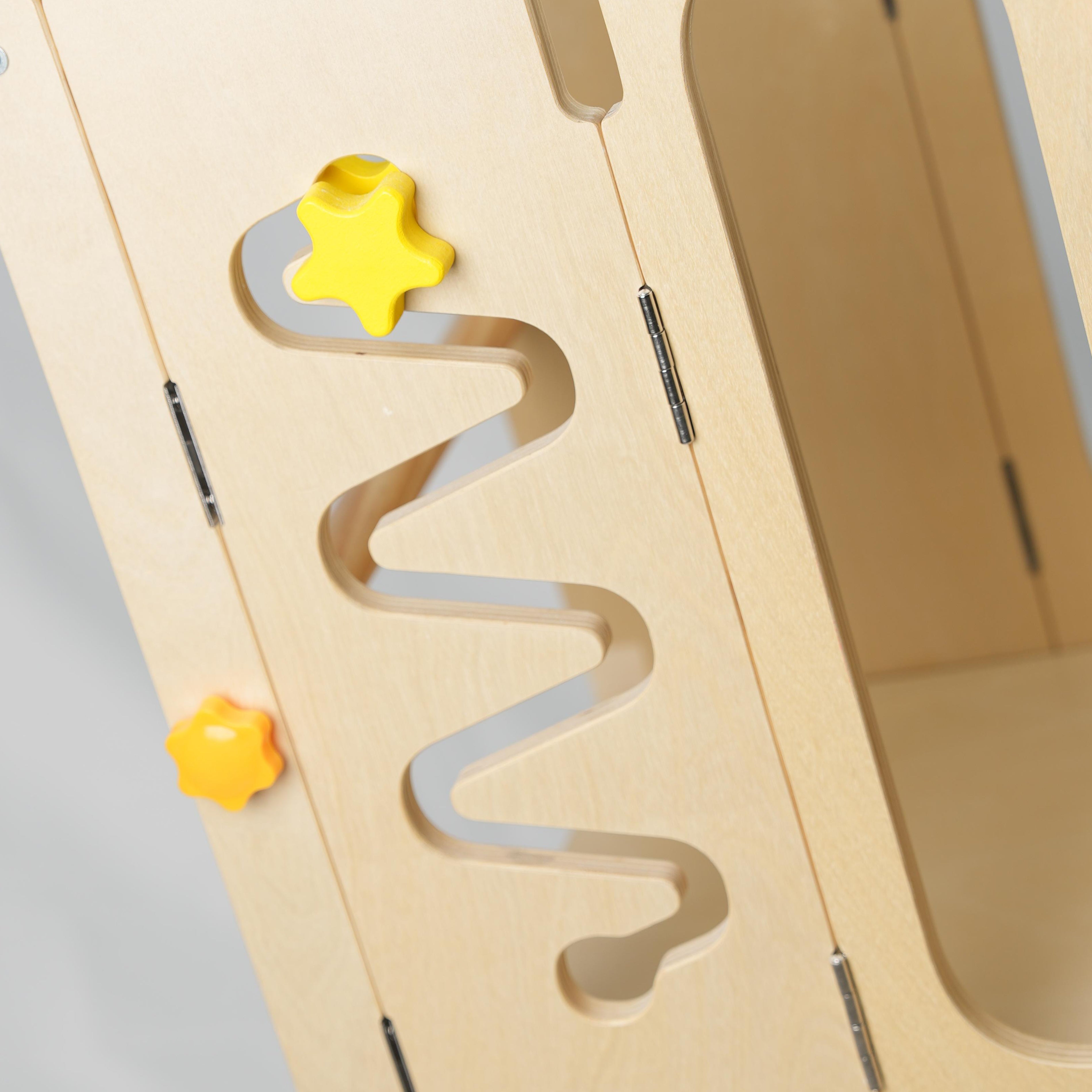 Close-up detail of the Hicooo learning tower's activity board features: a yellow gravity star sliding down a zig-zag track and colorful Montessori spinning gears.