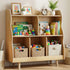 Hicooo styled wooden kids' bookshelf with wavy edges in a bright room, filled with children's books like 'Goodnight Moon', wooden toys, and woven storage baskets on the bottom shelf.