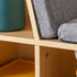 A close-up shot of the kids' wooden bookcase, highlighting the textured grey fabric of the reading bench cushion and the sturdy, smooth wooden joinery, showcasing the high-quality craftsmanship.