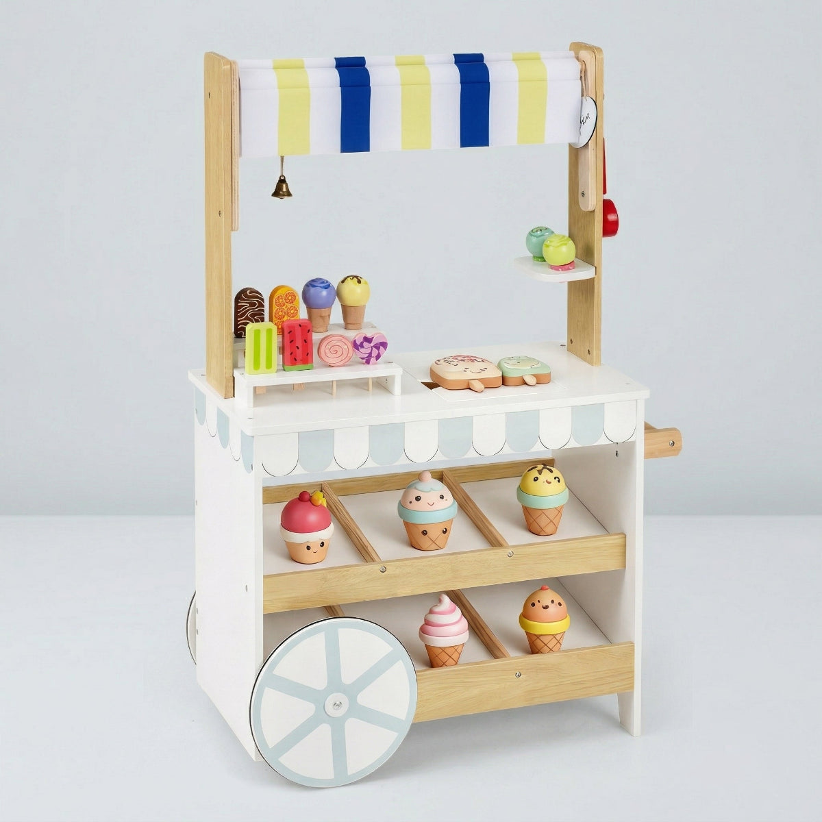 A studio product shot of a side view of a kids' wooden pretend play ice cream cart and grocery store playset on a white background. It displays the white frame, natural wood accents, folding awning structure, two large rear wheels, and side panel details without accessories.