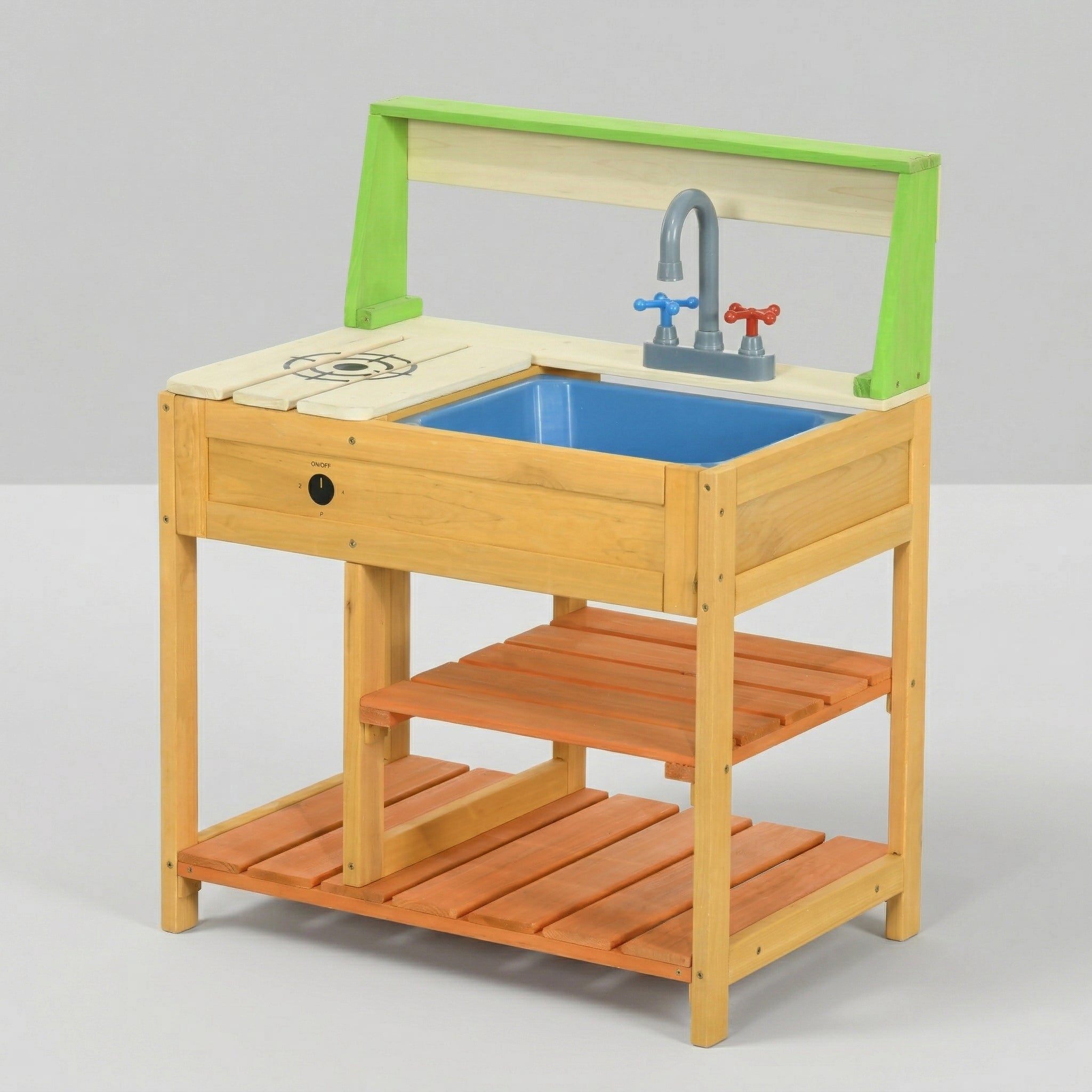 A studio product shot of a wooden pretend play kitchen on a plain light background. It clearly displays the natural wood frame, a green top accent, a blue plastic sink, a grey faucet, a painted stovetop element, a black control knob, and two tiers of slatted wooden storage shelves at the bottom.