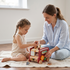 A mother and her toddler daughter sitting on the floor, happily playing with the top bead maze of the HiCOOO wooden animal bus activity cube.