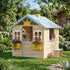 A lifestyle photograph capturing a rustic, natural fir wood children's outdoor playhouse set up on a grassy backyard lawn on a sunny day. It has multiple open windows and a small working door, surrounded by green foliage.