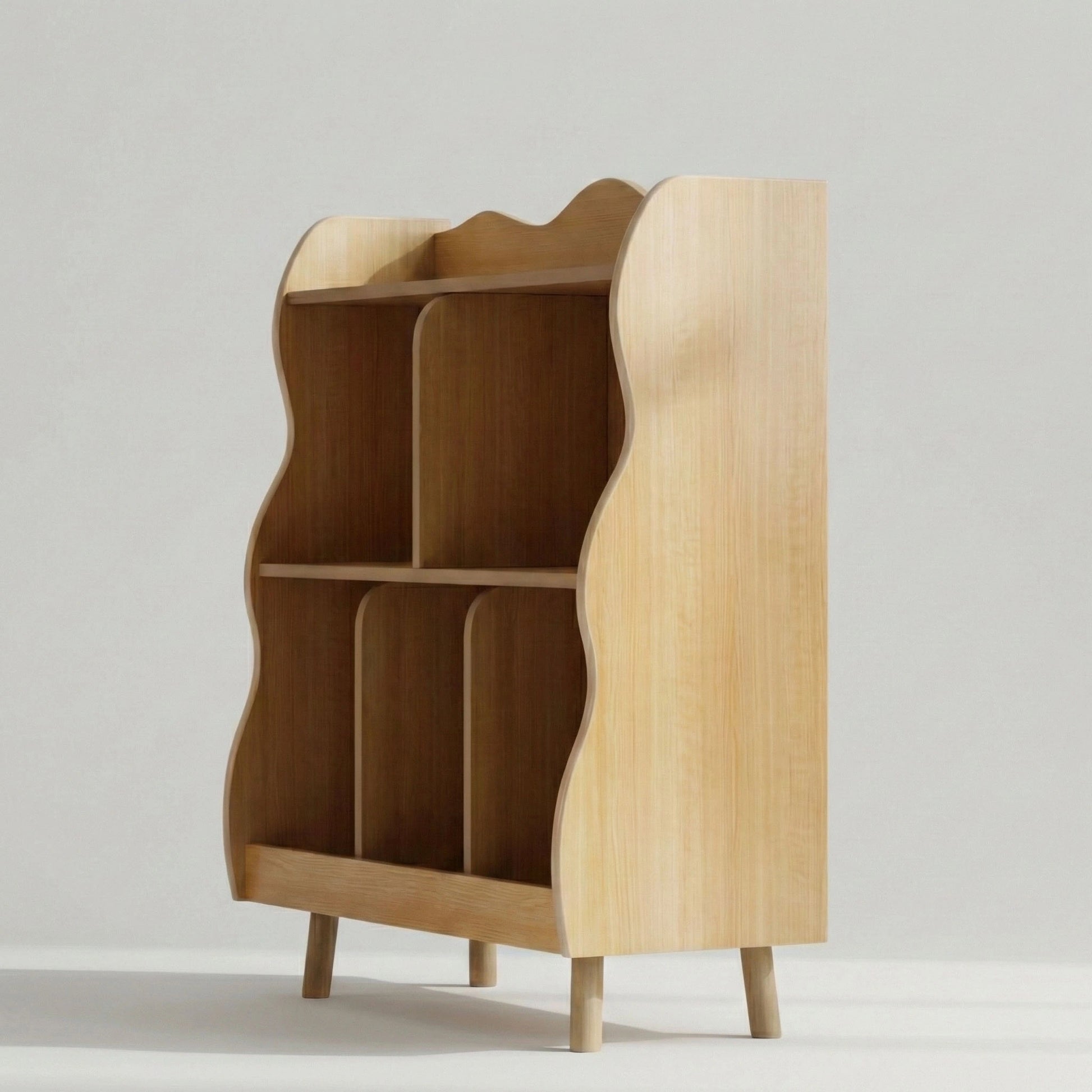 A side-angle view of a natural wood kids' bookshelf and toy organizer, highlighting its unique wavy edge design, multiple storage cubbies, and sturdy legs.