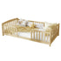 A light natural wood daybed with safety rails, styled with white bedding, a beige patterned blanket, and decorative pillows on a solid white background.