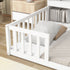 White crib with a pillow on a wooden floor in a room setting.