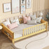 Children's bed with wooden frame and white mattress, surrounded by decorative pillows and framed pictures on the wall.