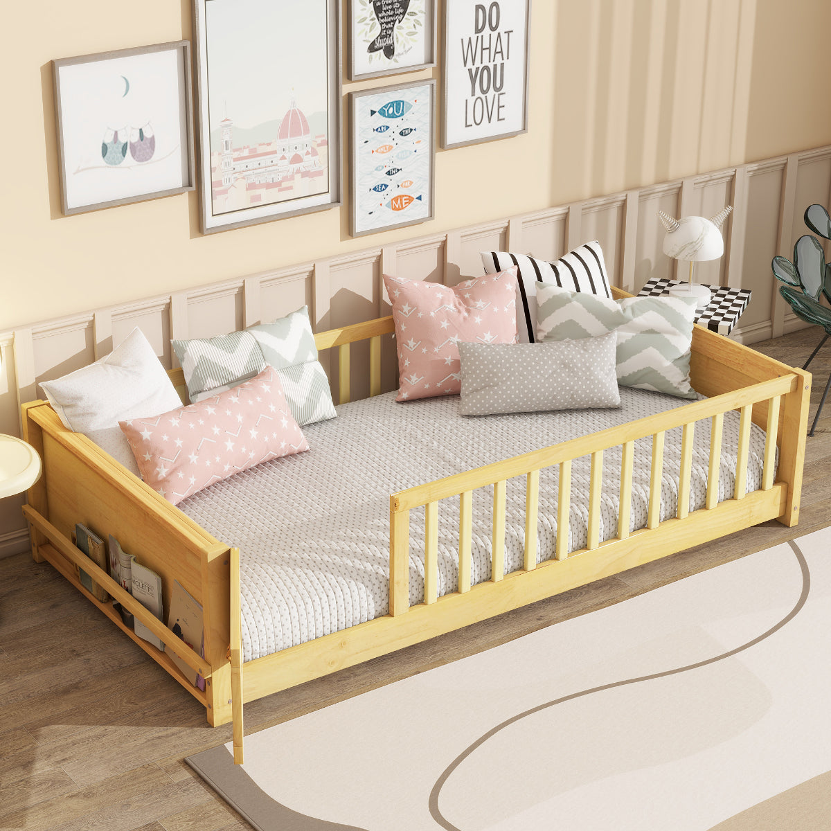 Children's bed with wooden frame and white mattress, surrounded by decorative pillows and framed pictures on the wall.