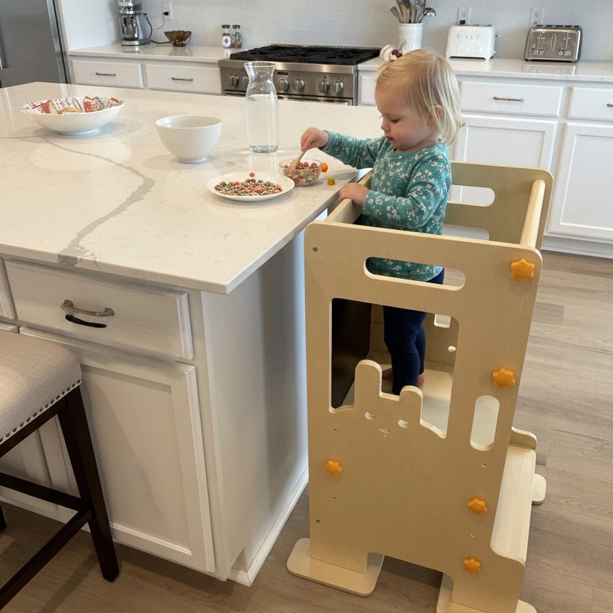 Happy toddler helping in the kitchen standing on HICOOO wooden learning tower. Safe montessori step stool for kids participating in cooking activities.