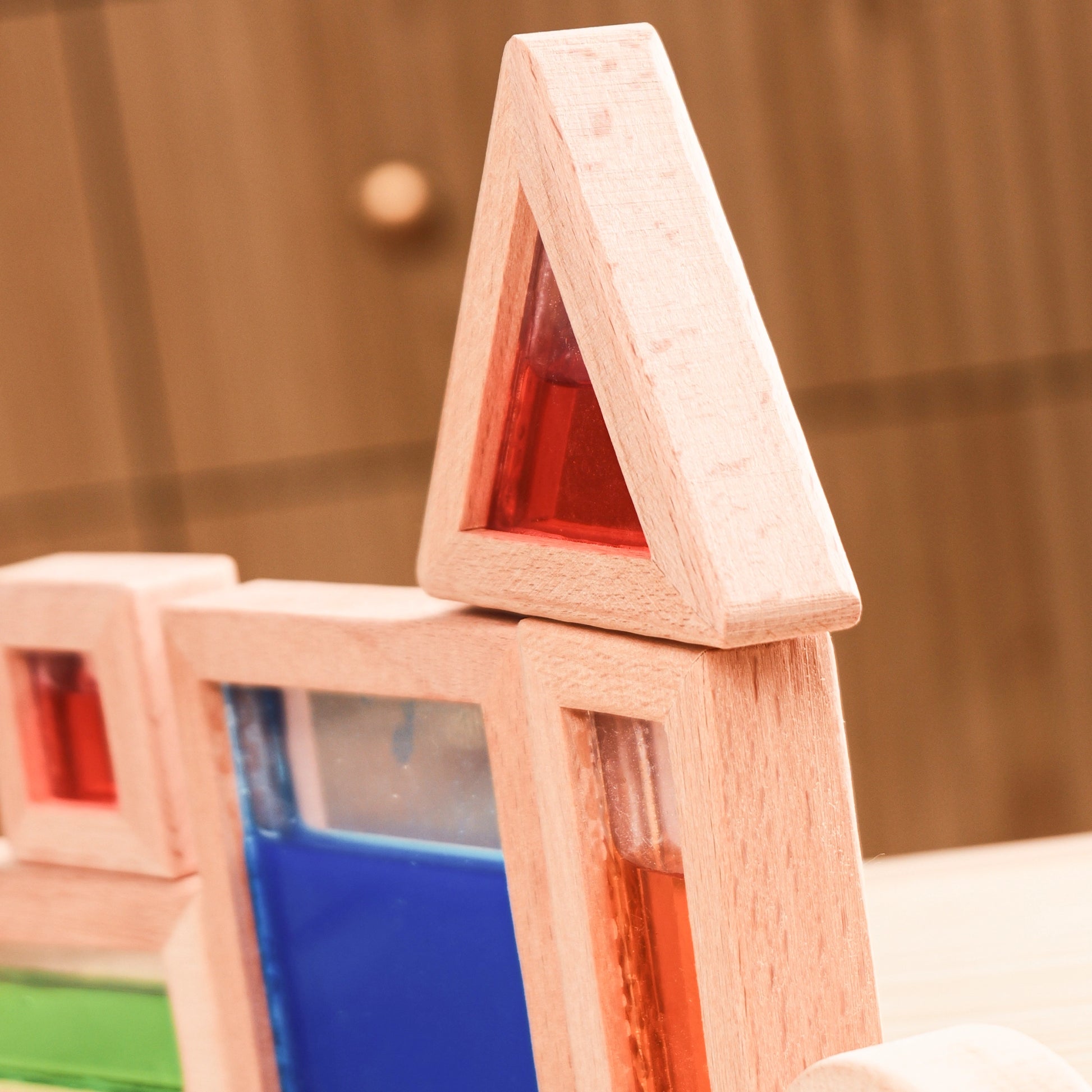 Close-up of wooden sensory blocks filled with vibrant blue and green translucent liquids reflecting light.
