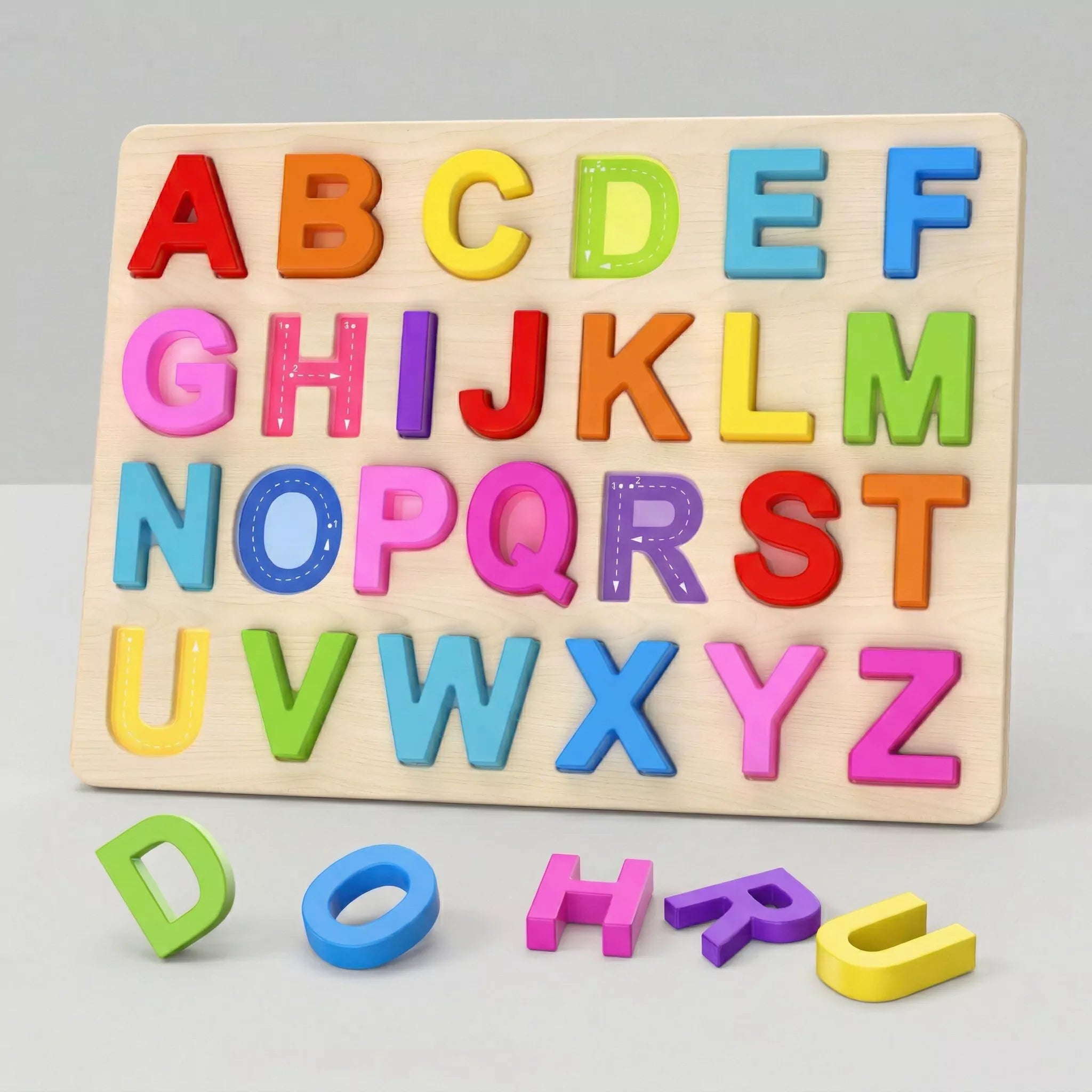 A colorful wooden alphabet puzzle board with chunky letters on a plain white background. The letters D, O, H, R, and U are placed in front of the board, revealing the tracing lines inside the slots.
